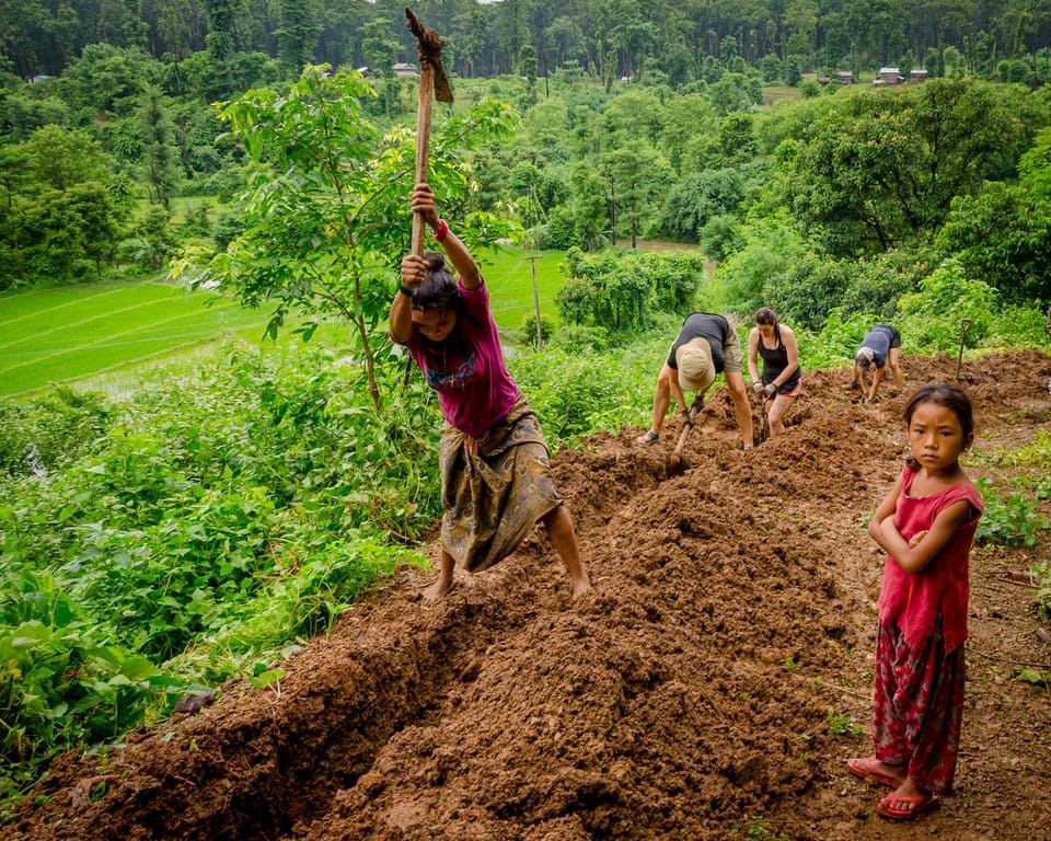 Village workers carrying materials along a hillside path